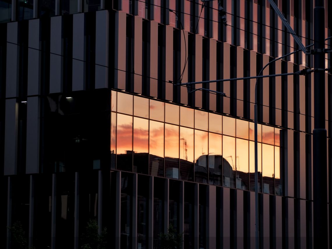 Regularny wzór przełamany przez zachód słońca odbijający się w szybach budynku Maraton w Poznaniu.