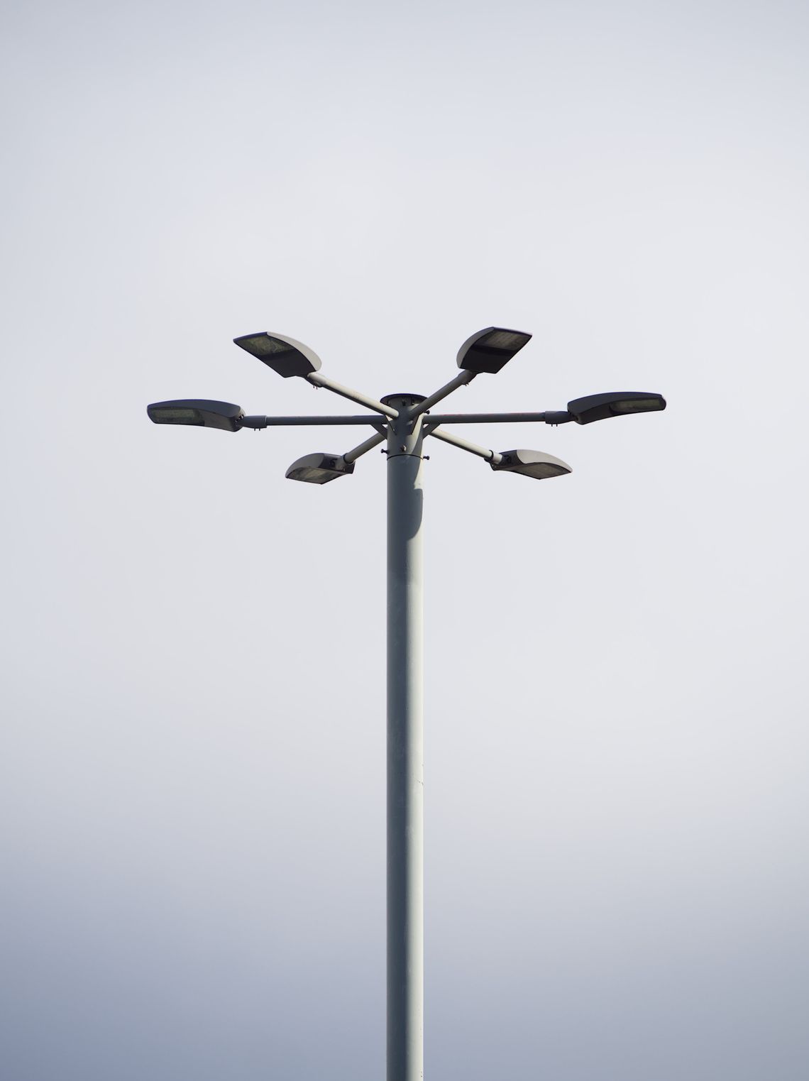 Górna część latarni rozgałęziającej się na 6 sosobnych lna tle zachmurzonego nieba.