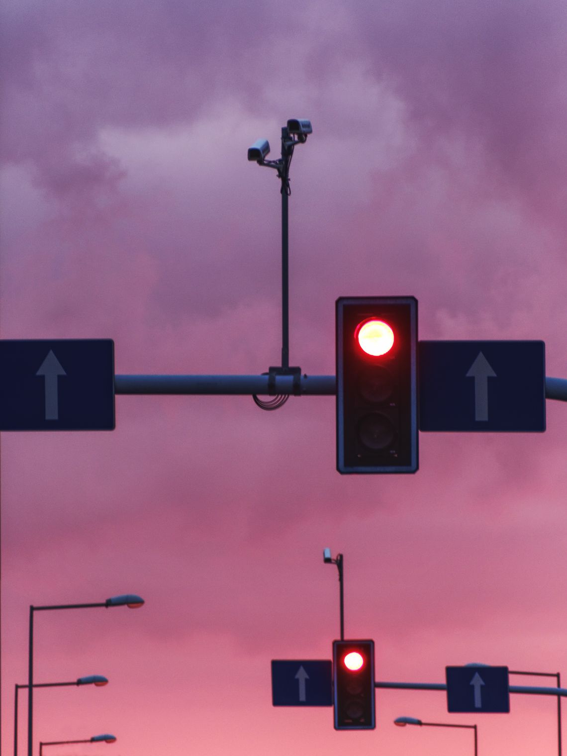 Sygnalizacja świetlna w dużym zbliżeniu, w tle różowe niebo.